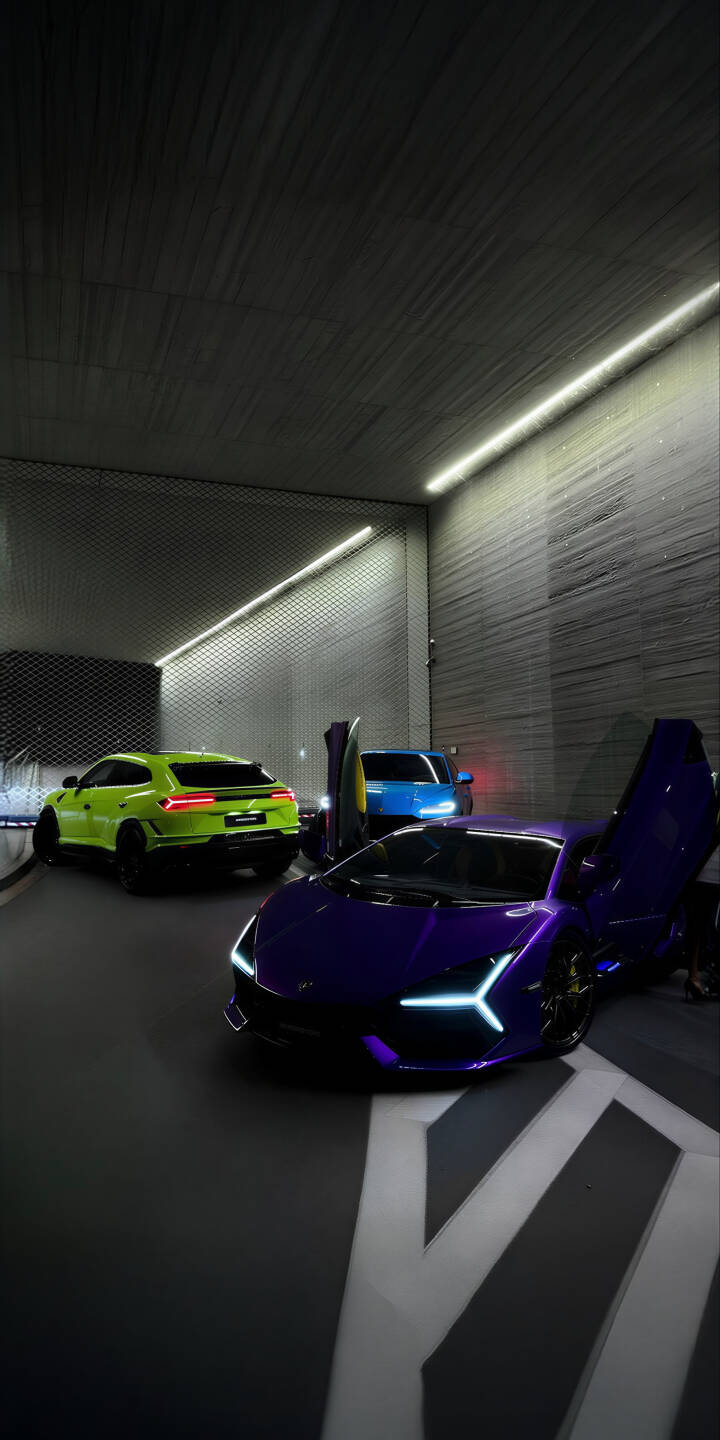 Immerse yourself in this stunning 4K Lamborghini cars wallpaper featuring a vibrant purple supercar with its iconic scissor doors open, a striking lime green Urus, and a sleek blue model, all illuminated by futuristic linear lighting in a modern garage. This dynamic wallpaper is perfect for your iPhone, bringing luxury automotive aesthetics to your mobile screen. | sports car iphone lamborghini urus huracan supercar mobile 4k wallpaper hd wallpaper purple lamborghini luxury cars exotic cars Immerse yourself in this stunning 4K Lamborghini cars wallpaper featuring a vibrant purple supercar with its iconic scissor doors open, a striking lime green Urus, and a sleek blue model, all illuminated by futuristic linear lighting in a modern garage. This dynamic wallpaper is perfect for your iPhone, bringing luxury automotive aesthetics to your mobile screen.