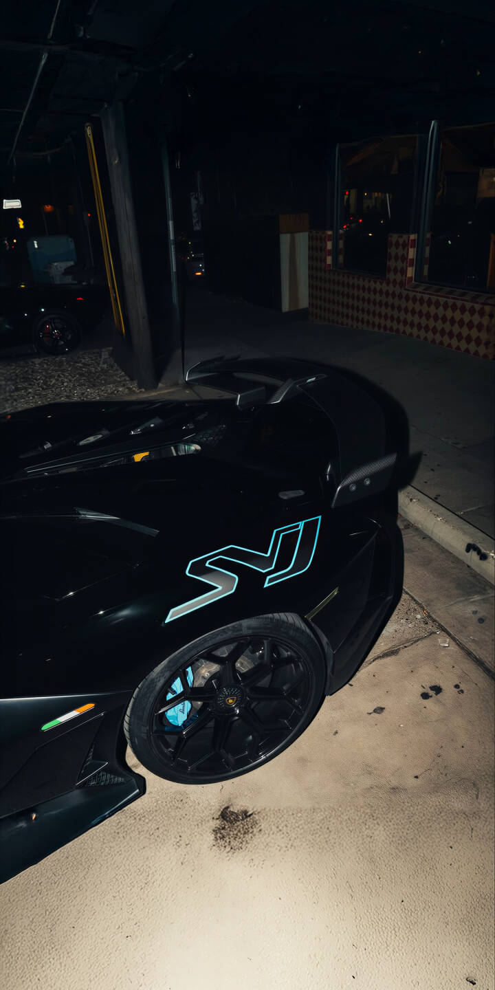 Elevate your iPhone screen with this stunning Lamborghini Aventador SVJ 4K wallpaper, featuring the sleek black supercar with its distinctive blue SVJ decal and matching blue brake calipers illuminated against the night sky. This high-resolution wallpaper perfectly captures the raw power and elegance of the Aventador SVJ, making it an ideal background for any automotive enthusiast. | iphone lamborghini supercar black car mobile 4k wallpaper hd wallpaper automotive exotic car lamborghini wallpaper night car aventador svj Elevate your iPhone screen with this stunning Lamborghini Aventador SVJ 4K wallpaper, featuring the sleek black supercar with its distinctive blue SVJ decal and matching blue brake calipers illuminated against the night sky. This high-resolution wallpaper perfectly captures the raw power and elegance of the Aventador SVJ, making it an ideal background for any automotive enthusiast.