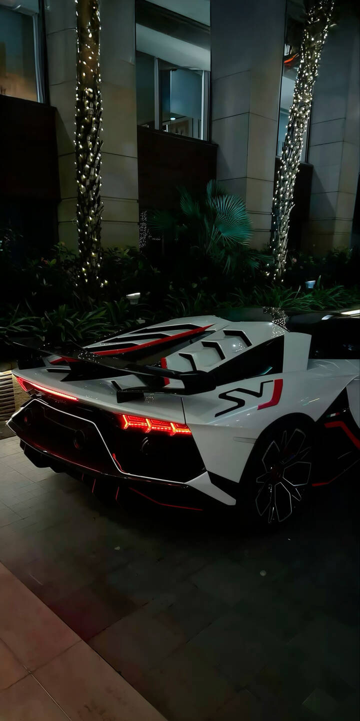 Elevate your device with this stunning Lamborghini Aventador SVJ 4K wallpaper, perfectly capturing the supercar's sleek white body, sharp red accents, and distinctive rear spoiler at night. This premium wallpaper is ideal for customizing your iPhone, showcasing the luxurious and powerful automotive design. | sports car iphone lamborghini supercar mobile luxury car 4k wallpaper hd wallpaper automotive exotic car aventador svj white lamborghini Elevate your device with this stunning Lamborghini Aventador SVJ 4K wallpaper, perfectly capturing the supercar's sleek white body, sharp red accents, and distinctive rear spoiler at night. This premium wallpaper is ideal for customizing your iPhone, showcasing the luxurious and powerful automotive design.