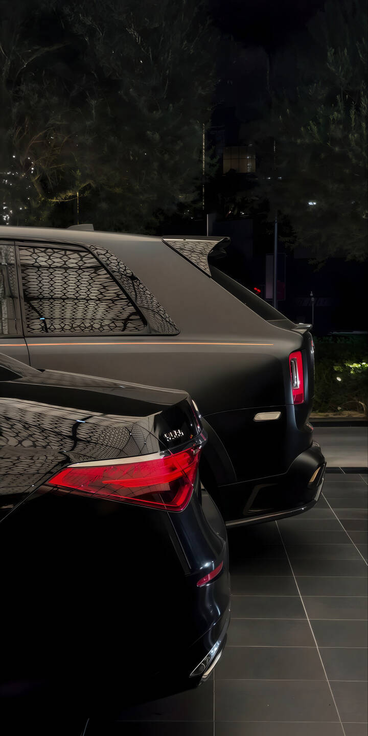 Elevate your iPhone screen with this luxurious 4K Rolls-Royce Cullinan wallpaper, featuring the iconic matte black SUV parked beside another sleek black luxury car with striking red taillights. This high-resolution wallpaper perfectly captures the opulent detailing and sophisticated ambiance of these premium automobiles. | suv iphone premium mobile matte black rolls-royce cullinan 4k wallpaper hd wallpaper car wallpaper dark mode luxury cars exotic cars Elevate your iPhone screen with this luxurious 4K Rolls-Royce Cullinan wallpaper, featuring the iconic matte black SUV parked beside another sleek black luxury car with striking red taillights. This high-resolution wallpaper perfectly captures the opulent detailing and sophisticated ambiance of these premium automobiles.