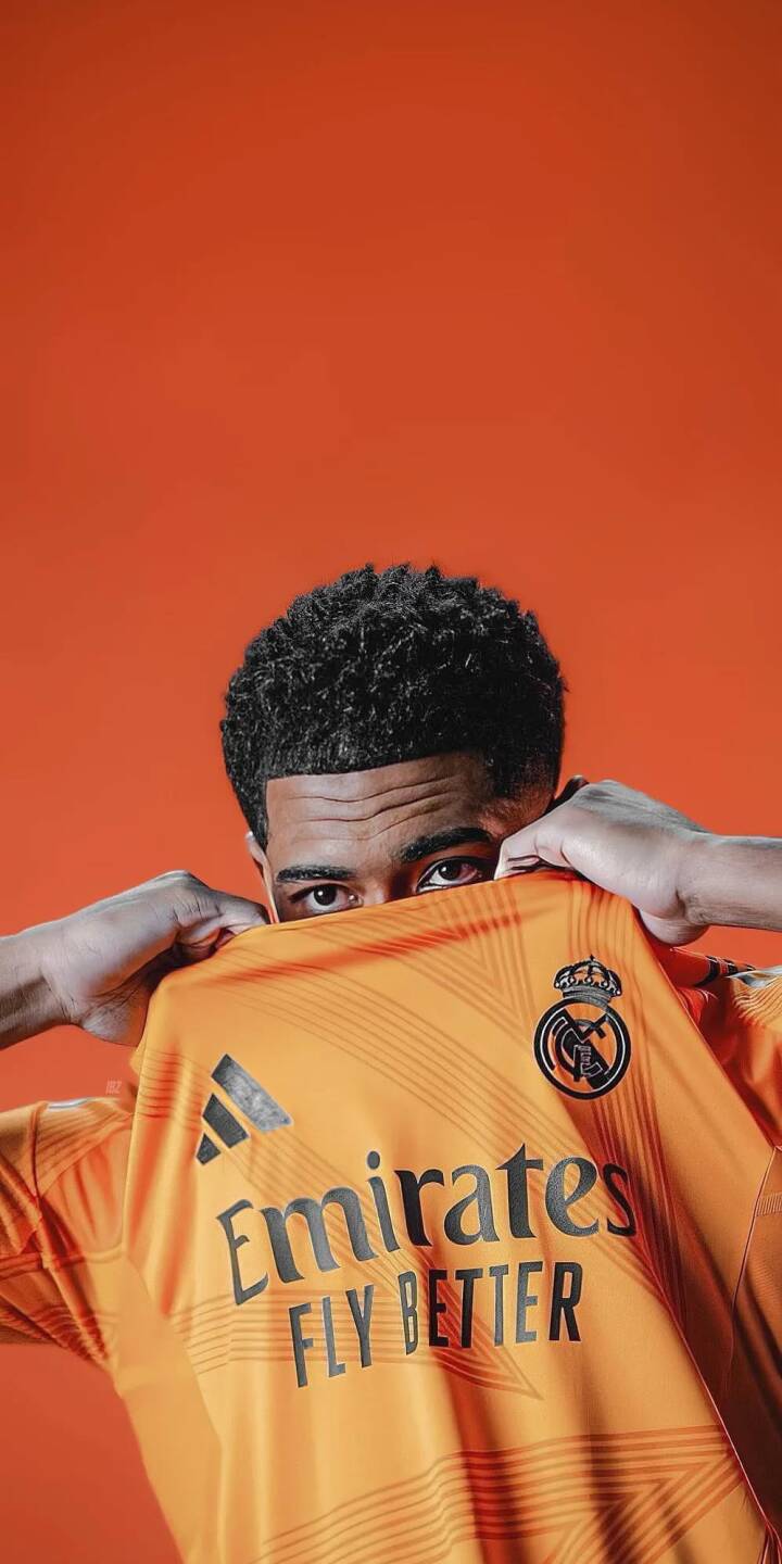 Elevate your iPhone with this stunning Jude Bellingham 4K wallpaper, showcasing the star peeking over his vibrant orange Real Madrid jersey against a matching orange background. This dynamic mobile wallpaper features Bellingham's curly hair and the iconic club crest, making it a perfect choice for any football fan. | sports football player iphone soccer real madrid jude bellingham bellingham mobile 4k wallpaper hd wallpaper orange jersey Elevate your iPhone with this stunning Jude Bellingham 4K wallpaper, showcasing the star peeking over his vibrant orange Real Madrid jersey against a matching orange background. This dynamic mobile wallpaper features Bellingham's curly hair and the iconic club crest, making it a perfect choice for any football fan.