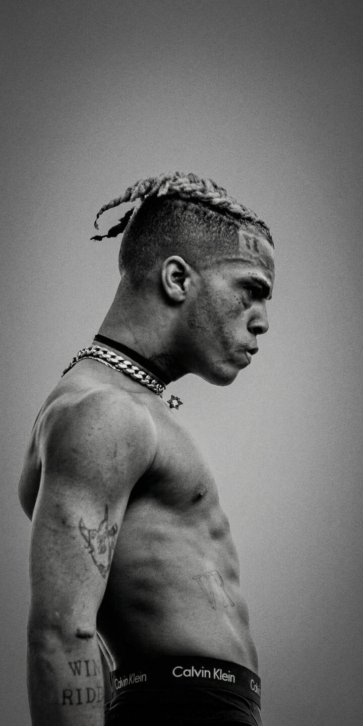 The monochromatic intensity of XXXTentacion's profile, highlighted by his distinct 'ALONE' facial tattoo and prominent chain necklace, makes for a powerful 4K wallpaper. This striking wallpaper for iPhone captures the artist's raw essence in stark detail. | aesthetic rapper music dark xxxtentacion iphone wallpaper black and white mobile 4k wallpaper hd wallpaper jahseh onfroy The monochromatic intensity of XXXTentacion's profile, highlighted by his distinct 'ALONE' facial tattoo and prominent chain necklace, makes for a powerful 4K wallpaper. This striking wallpaper for iPhone captures the artist's raw essence in stark detail.