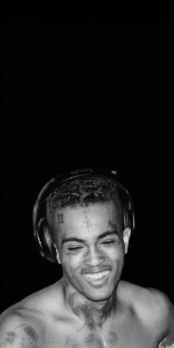 XXXTentacion's genuine, bright smile stands out in this captivating black and white 4K wallpaper, featuring his iconic facial tattoos and headphones against a minimalist background. This striking wallpaper is perfect for personalizing your iPhone. | aesthetic rapper music smile xxxtentacion iphone wallpaper black and white mobile 4k wallpaper hd wallpaper jahseh onfroy XXXTentacion's genuine, bright smile stands out in this captivating black and white 4K wallpaper, featuring his iconic facial tattoos and headphones against a minimalist background. This striking wallpaper is perfect for personalizing your iPhone.
