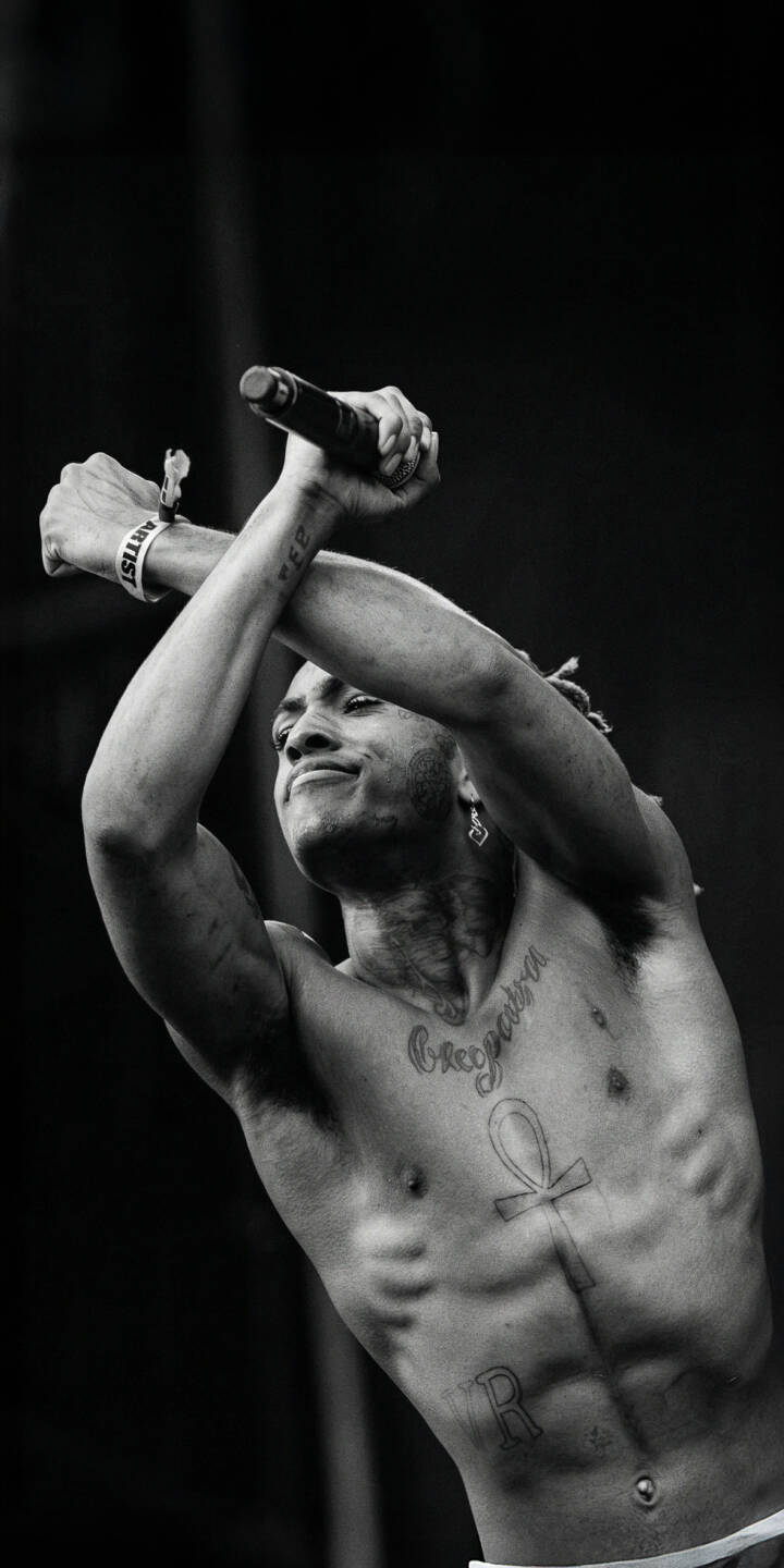 The striking black and white aesthetic highlights XXXTentacion's intense expression as he performs with arms crossed and microphone in hand in this captivating 4K wallpaper, featuring his iconic Ankh tattoo. This perfect concert wallpaper is a must-have for personalizing your iPhone screen. | rapper music concert xxxtentacion iphone wallpaper black and white mobile 4k wallpaper hd wallpaper tattoos jahseh onfroy The striking black and white aesthetic highlights XXXTentacion's intense expression as he performs with arms crossed and microphone in hand in this captivating 4K wallpaper, featuring his iconic Ankh tattoo. This perfect concert wallpaper is a must-have for personalizing your iPhone screen.