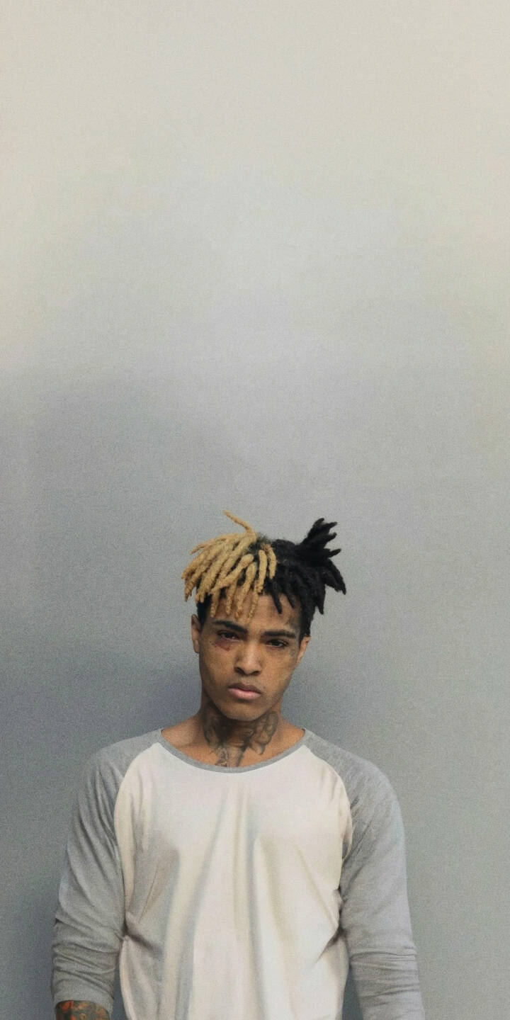 XXXTENTACION's iconic blonde and black dreadlocks, alongside his prominent facial tattoos and a somber expression, are sharply featured in this compelling 4K wallpaper - an essential iPhone wallpaper for fans looking to personalize their device. | aesthetic rapper portrait xxxtentacion mugshot iphone wallpaper hip hop mobile 4k wallpaper hd wallpaper jahseh onfroy XXXTENTACION's iconic blonde and black dreadlocks, alongside his prominent facial tattoos and a somber expression, are sharply featured in this compelling 4K wallpaper - an essential iPhone wallpaper for fans looking to personalize their device.