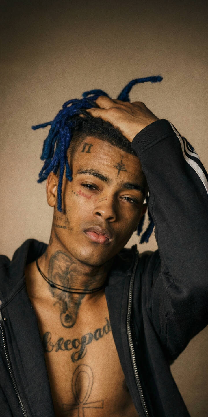 XXXTentacion's distinct blue dreadlocks and intricate facial tattoos are vividly showcased in this striking 4K wallpaper, making it a powerful visual statement for any iPhone screen. His ankh chest tattoo and reflective gaze define this must-have artist wallpaper. | aesthetic rapper music xxxtentacion iphone wallpaper mobile 4k wallpaper hd wallpaper tattoos jahseh onfroy blue dreads XXXTentacion's distinct blue dreadlocks and intricate facial tattoos are vividly showcased in this striking 4K wallpaper, making it a powerful visual statement for any iPhone screen. His ankh chest tattoo and reflective gaze define this must-have artist wallpaper.