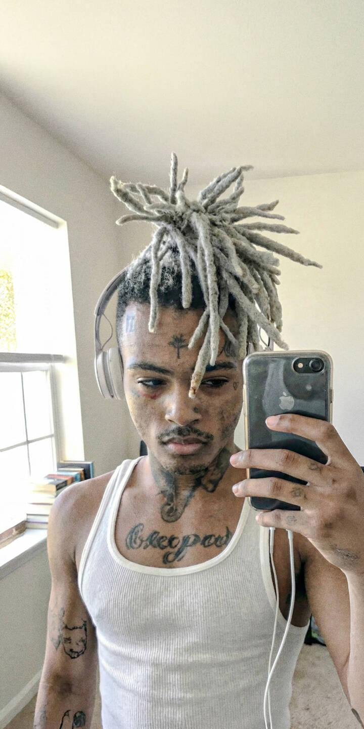 With a relaxed expression, XXXTentacion captures a mirror selfie, his signature grey dreadlocks and striking face tattoos rendered in stunning detail in this 4K wallpaper, making it an essential addition to any fan's iPhone wallpaper collection. | rapper selfie xxxtentacion iphone wallpaper x hip hop mobile 4k wallpaper hd wallpaper dreadlocks With a relaxed expression, XXXTentacion captures a mirror selfie, his signature grey dreadlocks and striking face tattoos rendered in stunning detail in this 4K wallpaper, making it an essential addition to any fan's iPhone wallpaper collection.