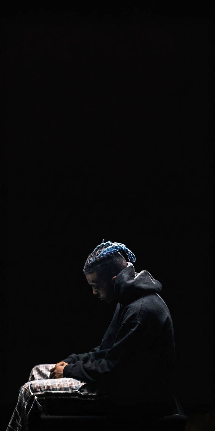 The striking blue dreadlocks of XXXTentacion are subtly illuminated against a deep dark background as he sits in pensive thought in this captivating 4K wallpaper. This profound image is a must-have iPhone wallpaper for fans seeking a deep, reflective mood. | aesthetic rapper dark xxxtentacion iphone wallpaper sad mobile 4k wallpaper hd wallpaper blue hair jahseh onfroy The striking blue dreadlocks of XXXTentacion are subtly illuminated against a deep dark background as he sits in pensive thought in this captivating 4K wallpaper. This profound image is a must-have iPhone wallpaper for fans seeking a deep, reflective mood.