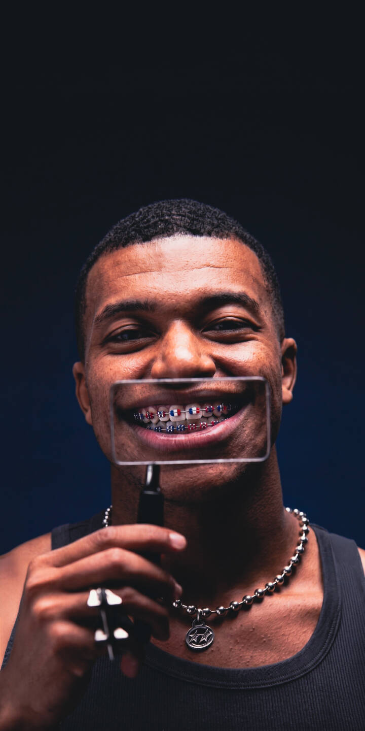 Kylian Mbappé's wide smile reveals vibrant French flag colored braces, magnified playfully in this striking 4K wallpaper. A perfect wallpaper for iPhone, it captures his charismatic expression against a dark background, highlighting his unique style. | football smile iphone mbappe soccer wallpaper mobile 4k wallpaper hd wallpaper kylian mbappe braces french Kylian Mbappé's wide smile reveals vibrant French flag colored braces, magnified playfully in this striking 4K wallpaper. A perfect wallpaper for iPhone, it captures his charismatic expression against a dark background, highlighting his unique style.