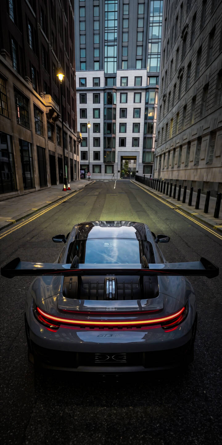 The striking red glow of a Porsche GT2 RS taillight illuminates a sleek grey rear, parked dramatically on a narrow city street. This dynamic 4K wallpaper for iPhone highlights the car's iconic spoiler and powerful presence, making it an essential wallpaper for enthusiasts. | aesthetic sports car city urban iphone porsche wallpaper mobile 4k wallpaper hd wallpaper automotive gt2 rs The striking red glow of a Porsche GT2 RS taillight illuminates a sleek grey rear, parked dramatically on a narrow city street. This dynamic 4K wallpaper for iPhone highlights the car's iconic spoiler and powerful presence, making it an essential wallpaper for enthusiasts.