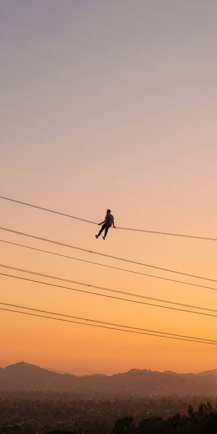 The solitary silhouette of a person balancing on electric wires against a breathtaking gradient sunset creates a mesmerizing 4K wallpaper. This stunning horizon view is a perfect wallpaper for iPhone, offering a unique blend of adventure and serenity. | aesthetic sunset iphone wallpaper silhouette mobile 4k wallpaper hd wallpaper gradient sky serene outdoors power lines The solitary silhouette of a person balancing on electric wires against a breathtaking gradient sunset creates a mesmerizing 4K wallpaper. This stunning horizon view is a perfect wallpaper for iPhone, offering a unique blend of adventure and serenity.