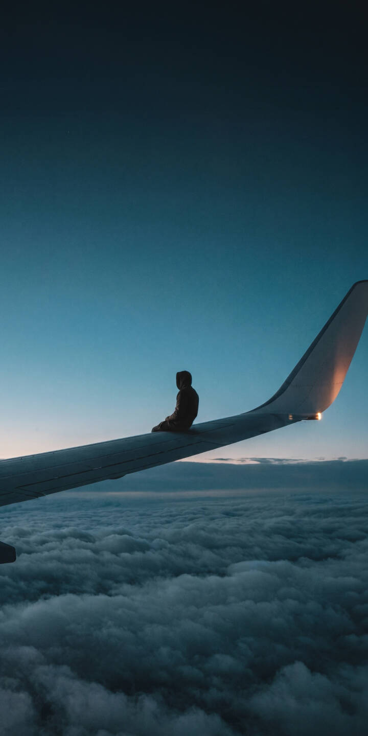 A lone figure sits calmly on an airplane wing, bathed in the soft glow of a twilight sky above an endless sea of fluffy clouds, creating a breathtaking 4K wallpaper for your iPhone; this serene and unique wallpaper captures a moment of ultimate tranquility. | travel iphone clouds airplane wallpaper mobile 4k wallpaper hd wallpaper dreamy adventure serene plane wing A lone figure sits calmly on an airplane wing, bathed in the soft glow of a twilight sky above an endless sea of fluffy clouds, creating a breathtaking 4K wallpaper for your iPhone; this serene and unique wallpaper captures a moment of ultimate tranquility.