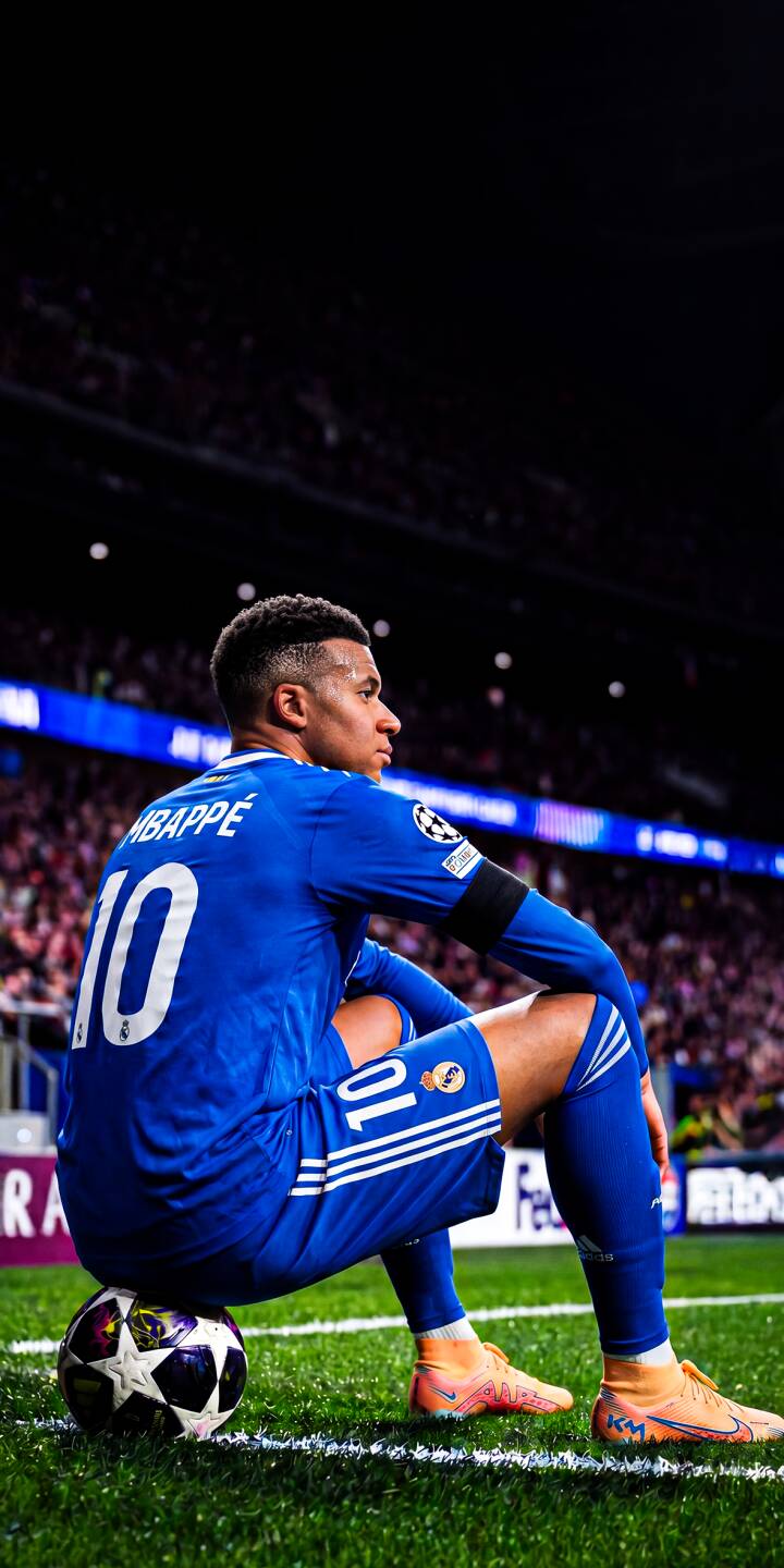 Mbappé's pensive profile against the bright stadium lights, with his blue #10 jersey and personalized orange boots visible, defines this stunning 4K wallpaper — a perfect mobile wallpaper for iPhone, showcasing a quiet moment for the football star. He sits confidently on a soccer ball on the vibrant green pitch. | football stadium athlete iphone mbappe soccer wallpaper mobile 4k wallpaper hd wallpaper champions league kylian mbappe Mbappé's pensive profile against the bright stadium lights, with his blue #10 jersey and personalized orange boots visible, defines this stunning 4K wallpaper — a perfect mobile wallpaper for iPhone, showcasing a quiet moment for the football star. He sits confidently on a soccer ball on the vibrant green pitch.