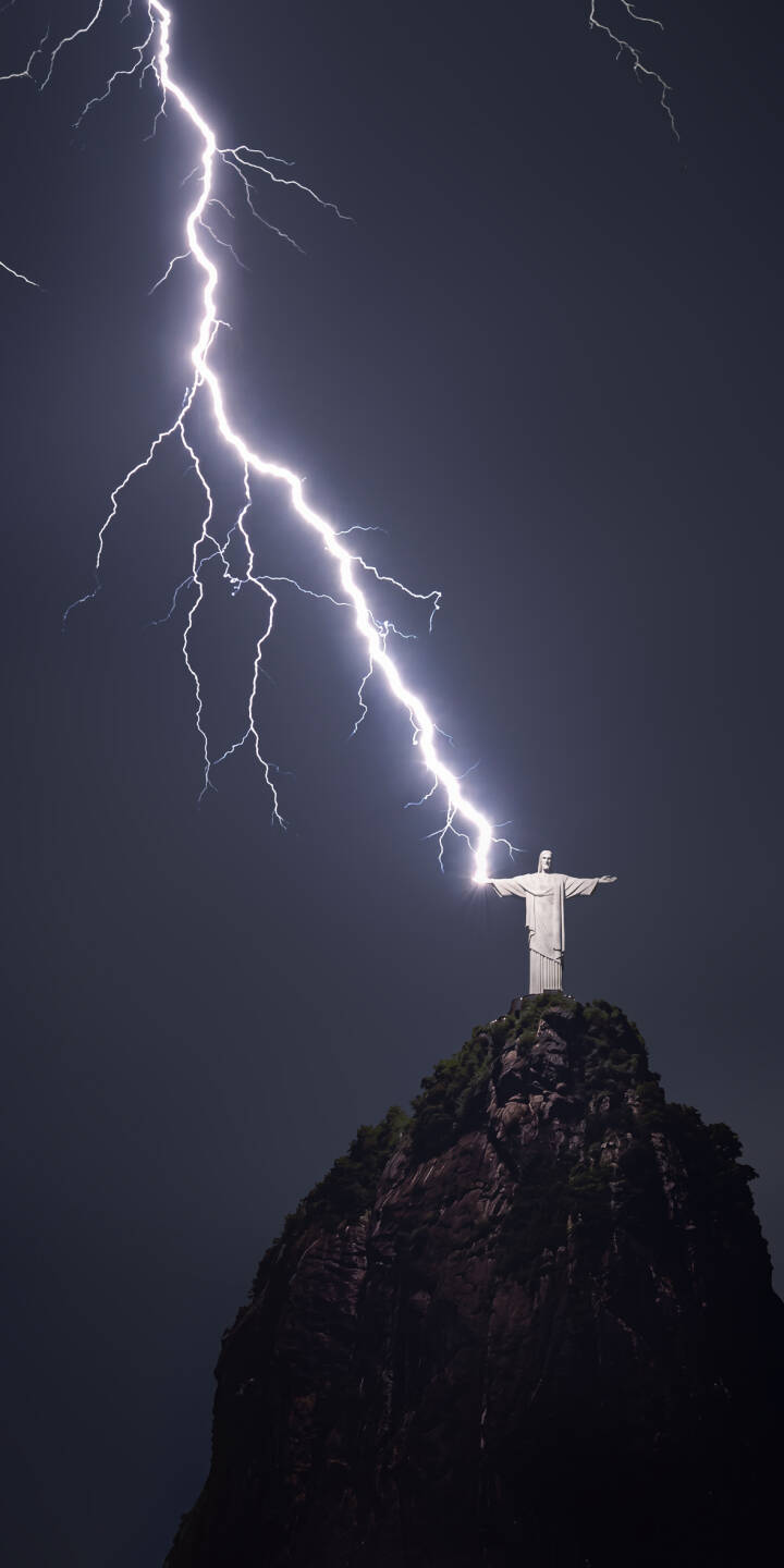 A massive bolt of lightning illuminates the dark sky, dramatically striking above the iconic Christ the Redeemer statue on Corcovado mountain in this breathtaking 4K wallpaper. This stunning natural spectacle makes an incredible wallpaper for iPhone fans. | lightning statue storm iphone wallpaper brazil mobile 4k wallpaper hd wallpaper iconic christ the redeemer rio de janeiro A massive bolt of lightning illuminates the dark sky, dramatically striking above the iconic Christ the Redeemer statue on Corcovado mountain in this breathtaking 4K wallpaper. This stunning natural spectacle makes an incredible wallpaper for iPhone fans.