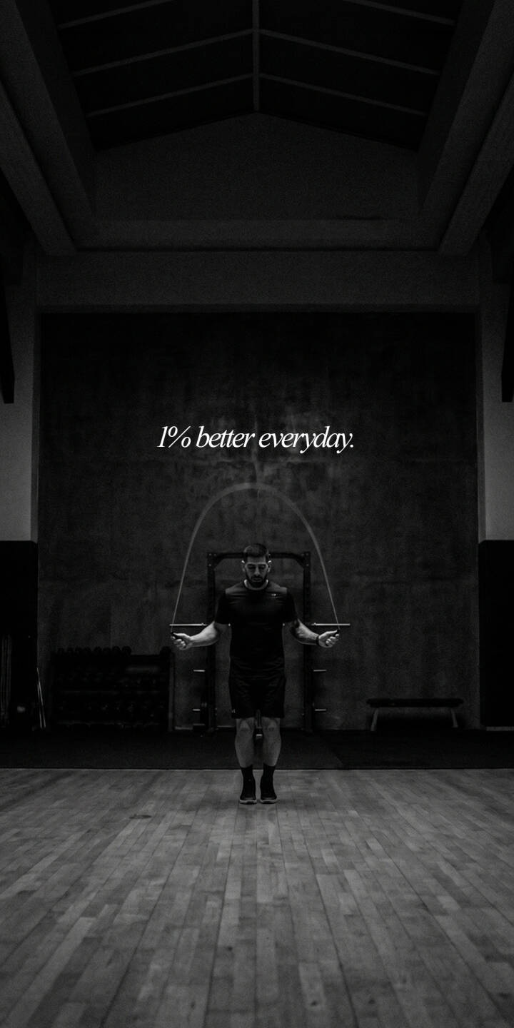 The impactful mantra "1% better everyday" is strikingly displayed above a man diligently skipping rope in this monochromatic 4K wallpaper, set within a vast, industrial gym. This motivational fitness wallpaper is a perfect reminder for your iPhone to pursue daily improvement. | quote gym motivation iphone wallpaper black and white mobile fitness 4k wallpaper hd wallpaper workout skip rope The impactful mantra "1% better everyday" is strikingly displayed above a man diligently skipping rope in this monochromatic 4K wallpaper, set within a vast, industrial gym. This motivational fitness wallpaper is a perfect reminder for your iPhone to pursue daily improvement.