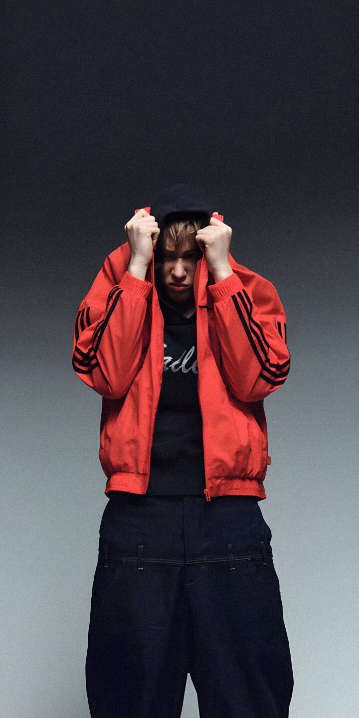 An intense expression is framed by a pulled-up hoodie in this 4K gritty urban wallpaper, featuring a subject in a bright red Adidas jacket and dark baggy pants. This striking wallpaper is perfect for any iPhone. | aesthetic man urban hoodie iphone wallpaper red jacket mobile 4k wallpaper hd wallpaper gritty street style An intense expression is framed by a pulled-up hoodie in this 4K gritty urban wallpaper, featuring a subject in a bright red Adidas jacket and dark baggy pants. This striking wallpaper is perfect for any iPhone.
