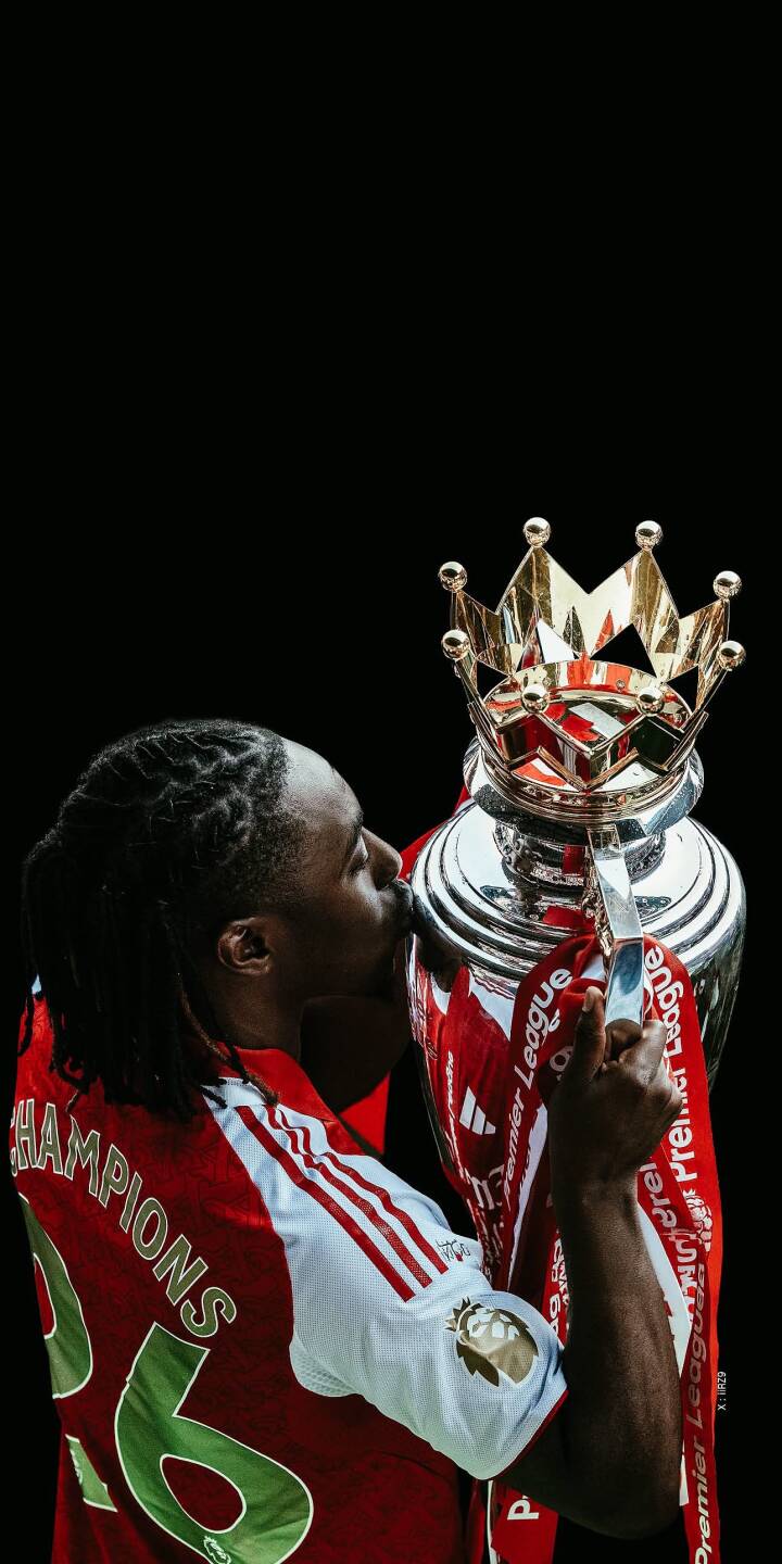 An athlete joyfully kisses his gleaming Premier League trophy, wearing a red and white jersey proudly displaying "CHAMPIONS" on its back, an iconic 4K wallpaper perfect for iPhone. This celebratory wallpaper captures the triumphant moment of a football victor against a stark black background. | sports football trophy celebration iphone premier league wallpaper champions mobile 4k wallpaper hd wallpaper An athlete joyfully kisses his gleaming Premier League trophy, wearing a red and white jersey proudly displaying "CHAMPIONS" on its back, an iconic 4K wallpaper perfect for iPhone. This celebratory wallpaper captures the triumphant moment of a football victor against a stark black background.