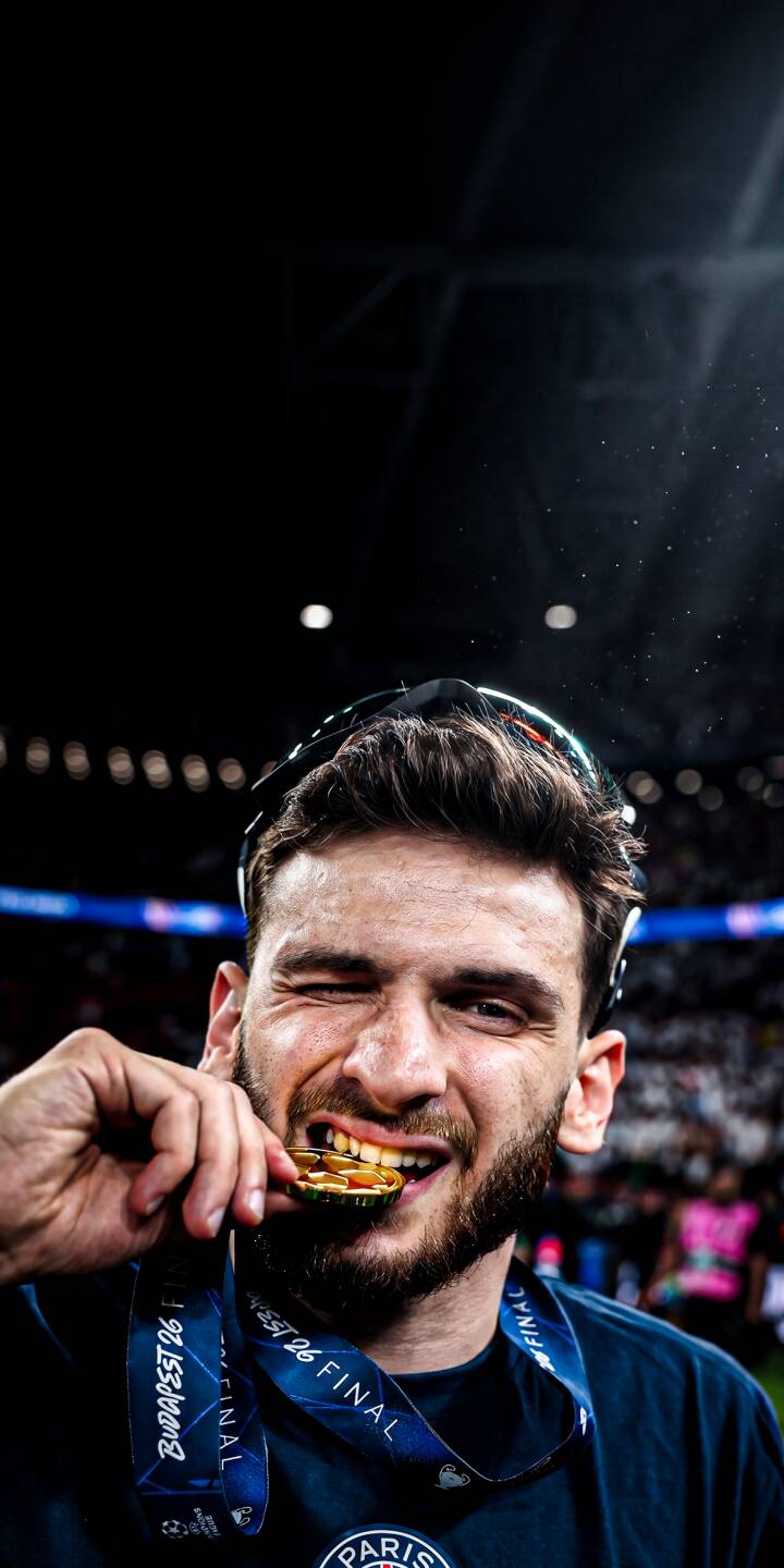 The shiny gold medal is playfully held between Khvicha Kvaratskhelia's teeth as he winks in triumphant celebration in this striking 4K wallpaper — a perfect champion's wallpaper for iPhone users. | celebration iphone wallpaper gold medal mobile footballer khvicha kvaratskhelia 4k wallpaper hd wallpaper champions league kvaratskhelia victory donnarumma kvara The shiny gold medal is playfully held between Khvicha Kvaratskhelia's teeth as he winks in triumphant celebration in this striking 4K wallpaper — a perfect champion's wallpaper for iPhone users.