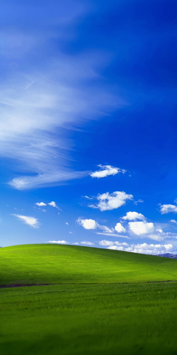 The famous vibrant green hillside of Windows XP Bliss stretches towards a brilliant blue sky dotted with fluffy white clouds in this stunning Frutiger Aero 4K wallpaper — a nostalgic mobile wallpaper perfect for iPhone. | landscape iphone nature wallpaper futuristic blue sky mobile frutiger aero 4k wallpaper hd wallpaper windows xp green hill iconic bliss windowsxp The famous vibrant green hillside of Windows XP Bliss stretches towards a brilliant blue sky dotted with fluffy white clouds in this stunning Frutiger Aero 4K wallpaper — a nostalgic mobile wallpaper perfect for iPhone.