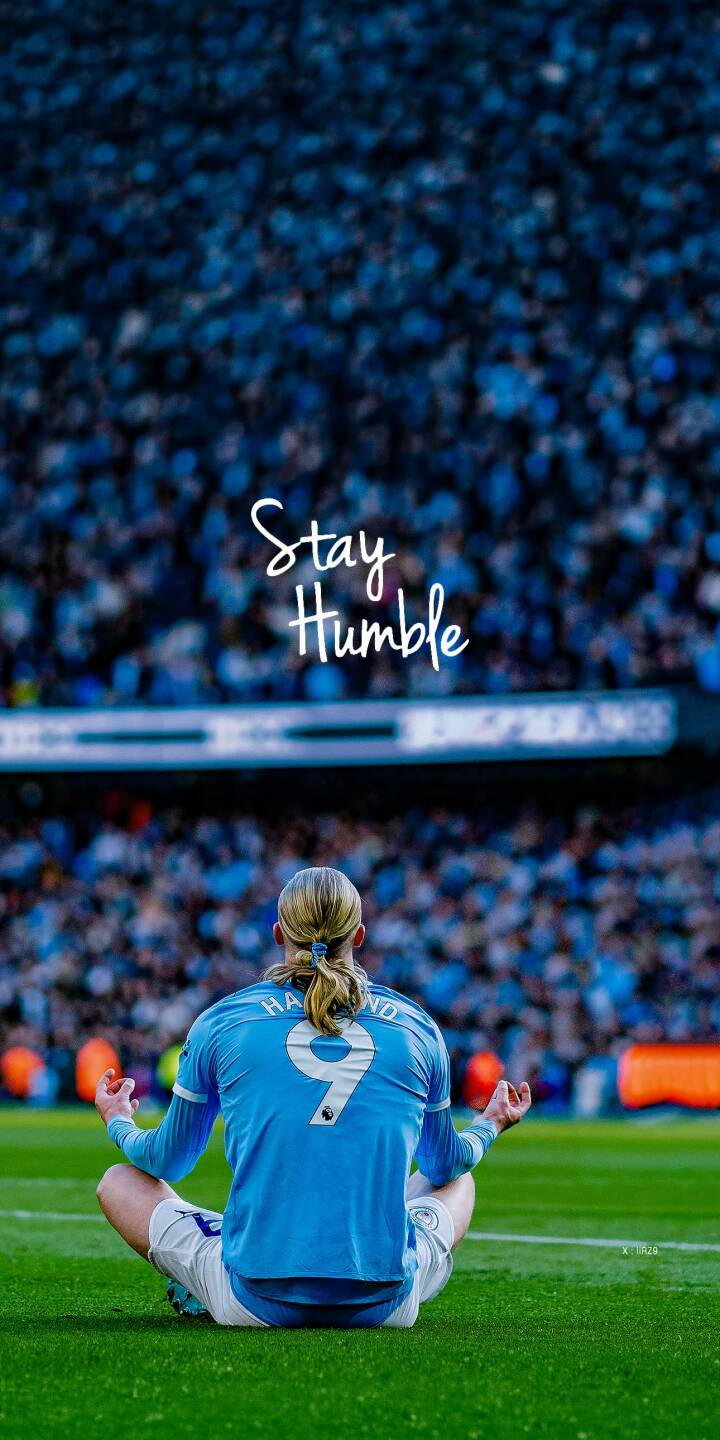 The inspiring phrase 'Stay Humble' floats above Erling Haaland as he sits in a meditative pose on the vibrant green pitch, making for a unique 4K wallpaper. This powerful image captures the soccer star's calm demeanor amidst a blurred stadium crowd, serving as an exceptional wallpaper for your iPhone. | football iphone soccer wallpaper haaland meditation manchester city mobile erling haaland 4k wallpaper hd wallpaper inspiring The inspiring phrase 'Stay Humble' floats above Erling Haaland as he sits in a meditative pose on the vibrant green pitch, making for a unique 4K wallpaper. This powerful image captures the soccer star's calm demeanor amidst a blurred stadium crowd, serving as an exceptional wallpaper for your iPhone.