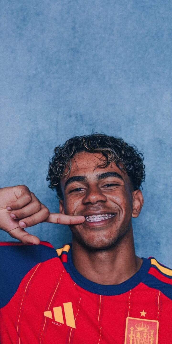 A young Spanish football player flashes a charming smile, proudly showing off his braces and curly highlighted hair against a textured blue background in this vibrant 4K wallpaper. It's the perfect wallpaper for iPhone, capturing his spirited and youthful energy. | football portrait smile player iphone soccer wallpaper mobile 4k wallpaper hd wallpaper spanish braces A young Spanish football player flashes a charming smile, proudly showing off his braces and curly highlighted hair against a textured blue background in this vibrant 4K wallpaper. It's the perfect wallpaper for iPhone, capturing his spirited and youthful energy.