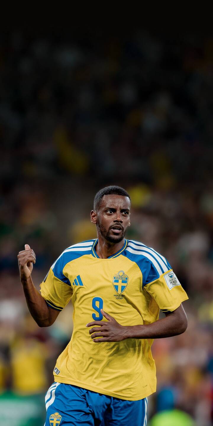 Alexander Isak, wearing his iconic yellow and blue Sweden jersey with the number 9, delivers an intense gaze in this powerful 4K wallpaper. This captivating wallpaper for iPhone showcases his focused expression against the vibrant, blurred stadium crowd. | sports iphone soccer wallpaper mobile 4k wallpaper hd wallpaper focused yellow jersey sweden alexander isak isak Alexander Isak, wearing his iconic yellow and blue Sweden jersey with the number 9, delivers an intense gaze in this powerful 4K wallpaper. This captivating wallpaper for iPhone showcases his focused expression against the vibrant, blurred stadium crowd.