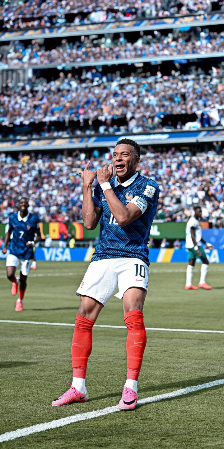Kylian Mbappé strikes a triumphant pose with hands raised high in this dynamic 4K wallpaper, showcasing his blue French national team jersey and vibrant pink cleats. A perfect mobile wallpaper for iPhone, capturing the thrill of a stadium-filled celebration. | sports football celebration iphone mbappe soccer wallpaper mobile 4k wallpaper hd wallpaper kylian mbappe french team Kylian Mbappé strikes a triumphant pose with hands raised high in this dynamic 4K wallpaper, showcasing his blue French national team jersey and vibrant pink cleats. A perfect mobile wallpaper for iPhone, capturing the thrill of a stadium-filled celebration.