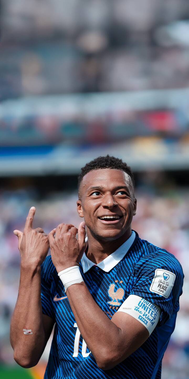 Kylian Mbappé smiles joyfully, making a heart-shaped hand gesture in his blue France jersey, making this a perfect 4K wallpaper for iPhone. This vibrant football wallpaper captures the celebratory spirit of the star player on the field. | sports football celebration iphone mbappe soccer wallpaper mobile france national team 4k wallpaper hd wallpaper kylian mbappe Kylian Mbappé smiles joyfully, making a heart-shaped hand gesture in his blue France jersey, making this a perfect 4K wallpaper for iPhone. This vibrant football wallpaper captures the celebratory spirit of the star player on the field.