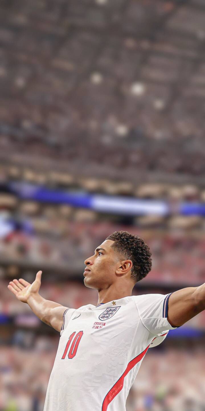 Jude Bellingham raises his arms wide, eyes fixed upward in triumph, wearing his crisp white England #10 jersey in this electrifying 4K football wallpaper — an essential wallpaper for iPhone fans showcasing the young star's celebration. | sports stadium celebration iphone wallpaper jude bellingham bellingham mobile footballer 4k wallpaper hd wallpaper england football Jude Bellingham raises his arms wide, eyes fixed upward in triumph, wearing his crisp white England #10 jersey in this electrifying 4K football wallpaper — an essential wallpaper for iPhone fans showcasing the young star's celebration.