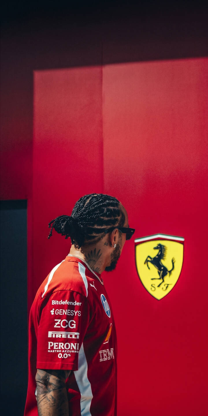 The striking yellow Ferrari emblem pops against the vibrant red wall as Lewis Hamilton, with his braided hair and sunglasses, looks on in this dynamic 4K wallpaper for iPhone. This detailed wallpaper captures his iconic presence alongside the legendary Scuderia symbol. | sports red iphone ferrari wallpaper f1 driver racer lewis hamilton formula 1 mobile 4k wallpaper hd wallpaper braids automotive iconic The striking yellow Ferrari emblem pops against the vibrant red wall as Lewis Hamilton, with his braided hair and sunglasses, looks on in this dynamic 4K wallpaper for iPhone. This detailed wallpaper captures his iconic presence alongside the legendary Scuderia symbol.