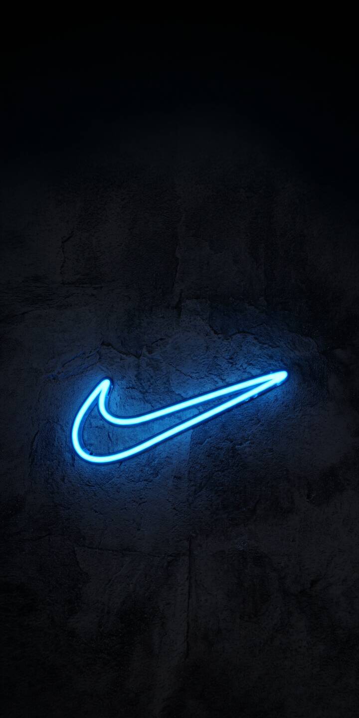 The vibrant blue neon Nike swoosh shines brilliantly, casting an electric glow against a dark, textured concrete wall in this striking 4K wallpaper - an essential wallpaper for iPhone enthusiasts. | blue dark neon glow nike iphone minimalist wallpaper mobile 4k wallpaper hd wallpaper swoosh The vibrant blue neon Nike swoosh shines brilliantly, casting an electric glow against a dark, textured concrete wall in this striking 4K wallpaper - an essential wallpaper for iPhone enthusiasts.