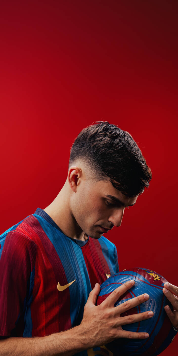 Pedri thoughtfully gazes at the blue and red football, his iconic FC Barcelona jersey vibrant against the solid red background in this striking 4K wallpaper — an essential wallpaper for iPhone showcasing the talented midfielder. | sports football iphone soccer barcelona wallpaper pedri fc barcelona mobile 4k wallpaper hd wallpaper red background Pedri thoughtfully gazes at the blue and red football, his iconic FC Barcelona jersey vibrant against the solid red background in this striking 4K wallpaper — an essential wallpaper for iPhone showcasing the talented midfielder.