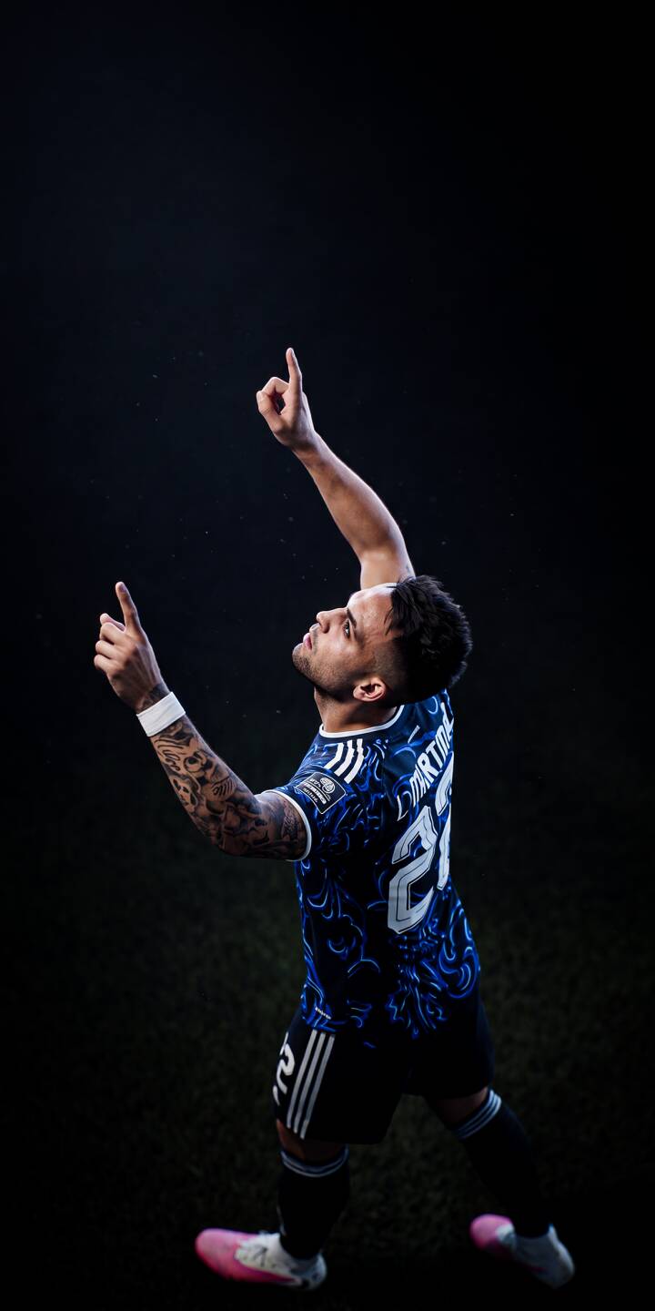 A soccer player in a vibrant blue patterned jersey lifts his arms, pointing skyward in a moment of triumph, making for an epic 4K wallpaper perfect for your iPhone. His detailed arm tattoos and focused expression add depth to this celebratory wallpaper. | sports football player athlete celebration iphone soccer wallpaper mobile 4k wallpaper hd wallpaper blue jersey A soccer player in a vibrant blue patterned jersey lifts his arms, pointing skyward in a moment of triumph, making for an epic 4K wallpaper perfect for your iPhone. His detailed arm tattoos and focused expression add depth to this celebratory wallpaper.