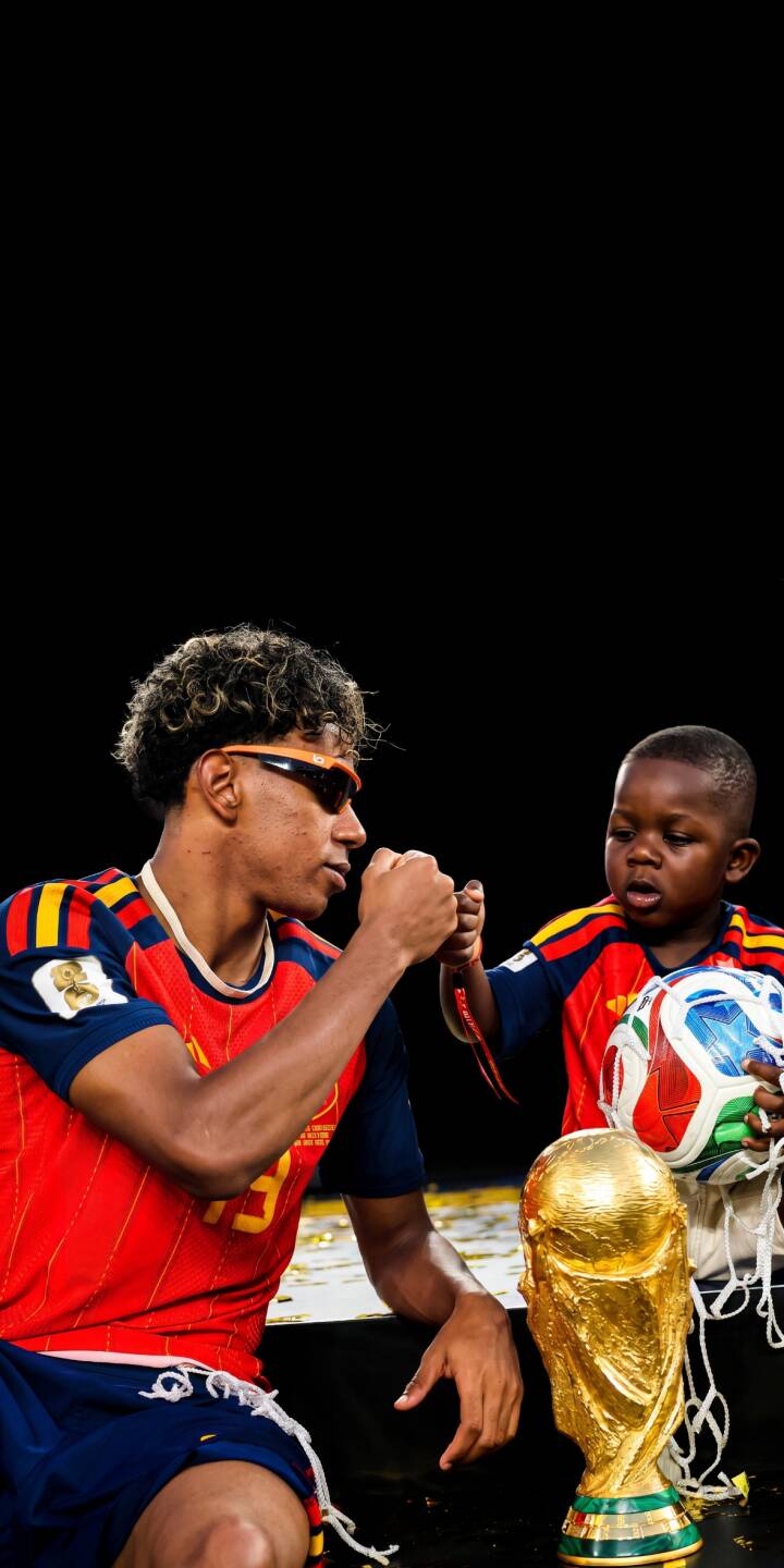 Lamine Yamal, sporting stylish sunglasses, shares a heartwarming moment with his younger brother, both in Spain jerseys, beside a gleaming golden trophy; this vibrant 4K wallpaper is a must-have for iPhone fans. | sports football trophy fan iphone soccer wallpaper mobile 4k wallpaper hd wallpaper heartwarming world cup Lamine Yamal, sporting stylish sunglasses, shares a heartwarming moment with his younger brother, both in Spain jerseys, beside a gleaming golden trophy; this vibrant 4K wallpaper is a must-have for iPhone fans.