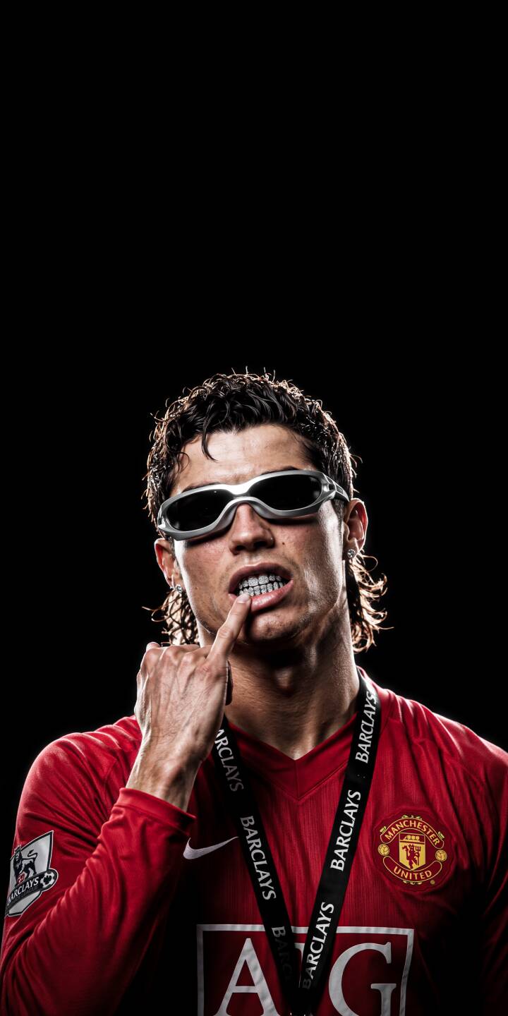 Cristiano Ronaldo rocks futuristic silver sunglasses and points at his unique teeth, sporting a shaggy mullet in his iconic Manchester United jersey in this edgy 4K wallpaper. This striking football legend wallpaper is a must-have for your iPhone. | football sunglasses iphone ronaldo wallpaper cr7 cristiano ronaldo mobile manchester united 4k wallpaper hd wallpaper edgy Cristiano Ronaldo rocks futuristic silver sunglasses and points at his unique teeth, sporting a shaggy mullet in his iconic Manchester United jersey in this edgy 4K wallpaper. This striking football legend wallpaper is a must-have for your iPhone.