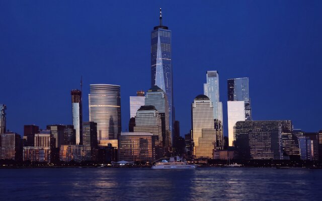 The striking deep blue twilight perfectly frames the illuminated New York City skyline, with the majestic Freedom Tower shining bright alongside other glowing buildings reflecting vividly on the water. This 4K wallpaper offers a breathtaking cityscape view, ideal for your MacOS or MacBook desktop. | night skyline wallpaper macos new york city nyc 4k wallpaper hd wallpaper cityscape macbook imac freedom tower The striking deep blue twilight perfectly frames the illuminated New York City skyline, with the majestic Freedom Tower shining bright alongside other glowing buildings reflecting vividly on the water. This 4K wallpaper offers a breathtaking cityscape view, ideal for your MacOS or MacBook desktop.