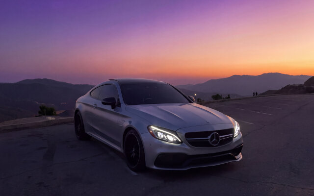 The vibrant purple and orange sunset sky frames this sleek silver Mercedes C-Class Coupe, making for a stunning 4K MacOS wallpaper. With its illuminated headlights and a mountainous backdrop, this high-quality image creates an aesthetically pleasing MacBook wallpaper that captures both luxury and nature. | aesthetic sunset mountains wallpaper macos mercedes benz luxury car 4k wallpaper hd wallpaper macbook imac mercedes c-class The vibrant purple and orange sunset sky frames this sleek silver Mercedes C-Class Coupe, making for a stunning 4K MacOS wallpaper. With its illuminated headlights and a mountainous backdrop, this high-quality image creates an aesthetically pleasing MacBook wallpaper that captures both luxury and nature.