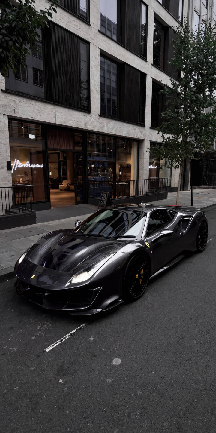 The sleek, dark grey Ferrari 488 sits gleaming under the city lights, parked gracefully beside a modern building, making this a stunning 4K wallpaper. This luxurious street scene is a perfect wallpaper for iPhone users looking for sophisticated automotive elegance. | aesthetic sports car city urban iphone ferrari supercar wallpaper mobile luxury car 4k wallpaper hd wallpaper The sleek, dark grey Ferrari 488 sits gleaming under the city lights, parked gracefully beside a modern building, making this a stunning 4K wallpaper. This luxurious street scene is a perfect wallpaper for iPhone users looking for sophisticated automotive elegance.