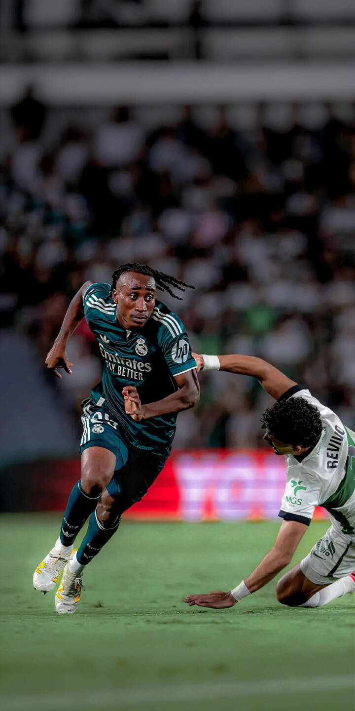 Eder Militao powers through the pitch in his dark green Real Madrid kit, intensely focused and evading an opponent, in this dynamic 4K wallpaper. This vibrant action wallpaper, perfectly optimized for iPhone, captures the intensity of the football match. | football iphone soccer real madrid dynamic wallpaper sport action mobile 4k wallpaper hd wallpaper eder militao Eder Militao powers through the pitch in his dark green Real Madrid kit, intensely focused and evading an opponent, in this dynamic 4K wallpaper. This vibrant action wallpaper, perfectly optimized for iPhone, captures the intensity of the football match.