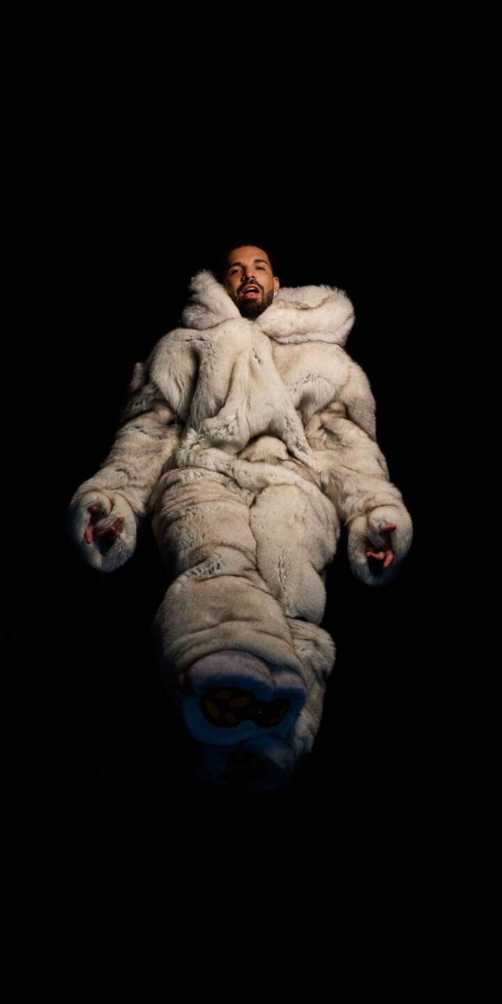 Drake emerges from a voluminous, light-colored fur suit against a deep black background in this stunning 4K wallpaper, creating a distinct and luxurious vibe; an essential aesthetic wallpaper for any iPhone. This unique Drake wallpaper brings a touch of modern hip-hop fashion to your screen. | artists Drake emerges from a voluminous, light-colored fur suit against a deep black background in this stunning 4K wallpaper, creating a distinct and luxurious vibe; an essential aesthetic wallpaper for any iPhone. This unique Drake wallpaper brings a touch of modern hip-hop fashion to your screen.