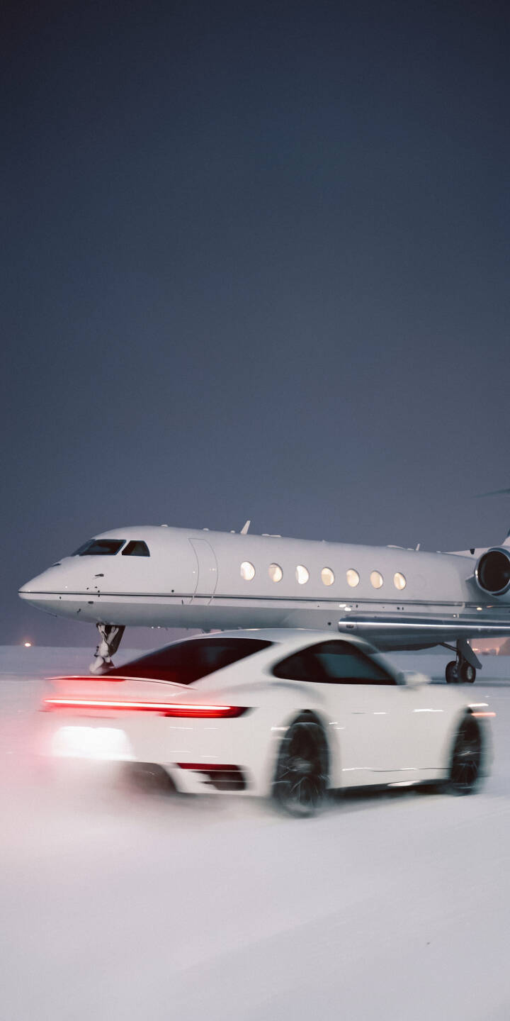 Red blurred taillights on the white Porsche signal its swift movement past a luxurious private jet in this captivating 4K wallpaper. Perfect for an iPhone, this wallpaper captures the essence of luxury travel and speed against a pristine snowy backdrop. | night snow iphone porsche private jet wallpaper speed mobile luxury car 4k wallpaper hd wallpaper Red blurred taillights on the white Porsche signal its swift movement past a luxurious private jet in this captivating 4K wallpaper. Perfect for an iPhone, this wallpaper captures the essence of luxury travel and speed against a pristine snowy backdrop.
