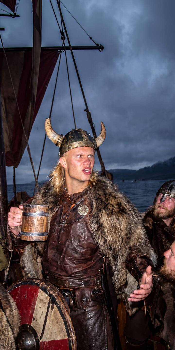 Erling Haaland's intense gaze under a horned helmet captures the spirit of a fierce Norse warrior, cloaked in fur and leather, as he grips a wooden mug on a Viking longship. This stunning 4K wallpaper offers an epic mobile wallpaper experience for your iPhone. | iphone wallpaper haaland mobile erling haaland 4k wallpaper hd wallpaper epic viking historical longship norse Erling Haaland's intense gaze under a horned helmet captures the spirit of a fierce Norse warrior, cloaked in fur and leather, as he grips a wooden mug on a Viking longship. This stunning 4K wallpaper offers an epic mobile wallpaper experience for your iPhone.