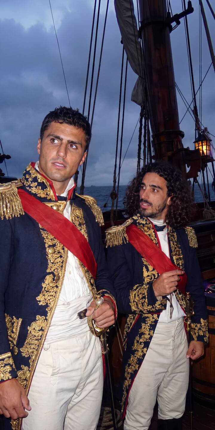 Golden embroidered uniforms gleam against the dark, overcast sky as two historic naval officers stand proudly on a ship's deck in this captivating 4K wallpaper, making it a perfect period wallpaper for your iPhone. | iphone wallpaper ship mobile 4k wallpaper hd wallpaper adventure maritime naval officers historic uniform gold embroidery period drama Golden embroidered uniforms gleam against the dark, overcast sky as two historic naval officers stand proudly on a ship's deck in this captivating 4K wallpaper, making it a perfect period wallpaper for your iPhone.