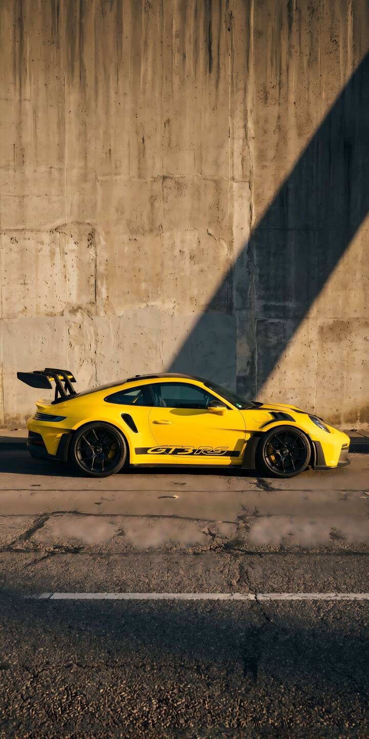 The vibrant yellow Porsche GT3 RS with its striking rear wing gleams under the sun against a rough concrete wall in this incredible 4K wallpaper. This stunning performance car wallpaper is perfect for your iPhone, showcasing sleek black accents and a long, dramatic shadow. | yellow porsche The vibrant yellow Porsche GT3 RS with its striking rear wing gleams under the sun against a rough concrete wall in this incredible 4K wallpaper. This stunning performance car wallpaper is perfect for your iPhone, showcasing sleek black accents and a long, dramatic shadow.