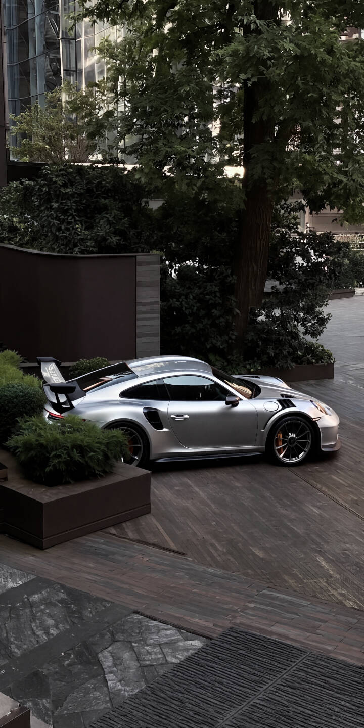 The striking silver Porsche 911 GT3 RS gleams, showcasing its aggressive rear wing and distinctive side vents in this upscale 4K wallpaper. This luxury sports car wallpaper is a perfect fit for any iPhone. | sports car urban iphone porsche luxury wallpaper mobile silver car gt3 rs 4k wallpaper hd wallpaper sleek The striking silver Porsche 911 GT3 RS gleams, showcasing its aggressive rear wing and distinctive side vents in this upscale 4K wallpaper. This luxury sports car wallpaper is a perfect fit for any iPhone.