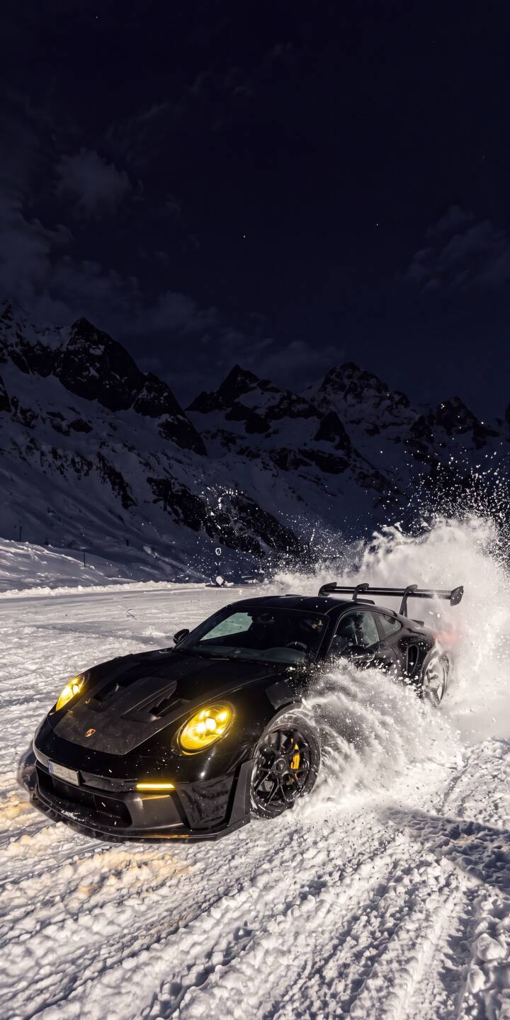 A powerful black Porsche 911 GT3 RS kicks up a spectacular cloud of snow and ice as its bright yellow headlights pierce the winter night in this stunning 4K wallpaper for iPhone. This dynamic automotive wallpaper captures raw power amidst a snowy mountain backdrop. | sports car snow winter drift iphone porsche wallpaper mobile 4k wallpaper hd wallpaper automotive 911 gt3 rs A powerful black Porsche 911 GT3 RS kicks up a spectacular cloud of snow and ice as its bright yellow headlights pierce the winter night in this stunning 4K wallpaper for iPhone. This dynamic automotive wallpaper captures raw power amidst a snowy mountain backdrop.
