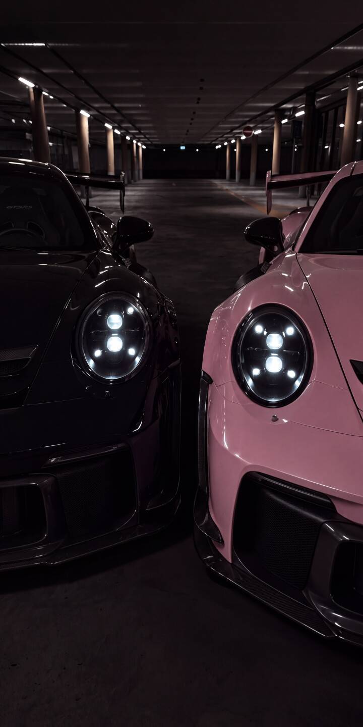 Bright LED headlights pierce the darkness of a parking garage, highlighting a stunning black Porsche and a vibrant pink Porsche GT3 side-by-side in this dynamic 4K wallpaper. This captivating automotive wallpaper is perfect for personalizing your iPhone. | sports car iphone porsche wallpaper mobile luxury car headlights pink car 4k wallpaper hd wallpaper dark aesthetic porsche gt3 Bright LED headlights pierce the darkness of a parking garage, highlighting a stunning black Porsche and a vibrant pink Porsche GT3 side-by-side in this dynamic 4K wallpaper. This captivating automotive wallpaper is perfect for personalizing your iPhone.