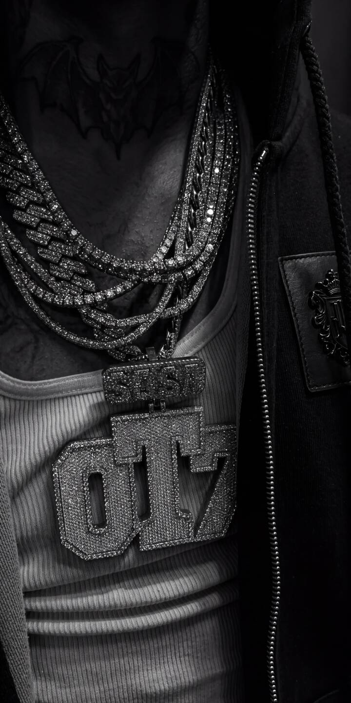 Glistening diamond chains and a prominent OT7 pendant command attention in this striking grayscale 4K wallpaper, featuring a detailed bat tattoo on the neck " a perfect wallpaper for iPhone users seeking a bold aesthetic. | iphone wallpaper drip fashion grayscale mobile 4k wallpaper hd wallpaper iced out diamond chains ot7 bat tattoo Glistening diamond chains and a prominent OT7 pendant command attention in this striking grayscale 4K wallpaper, featuring a detailed bat tattoo on the neck " a perfect wallpaper for iPhone users seeking a bold aesthetic.