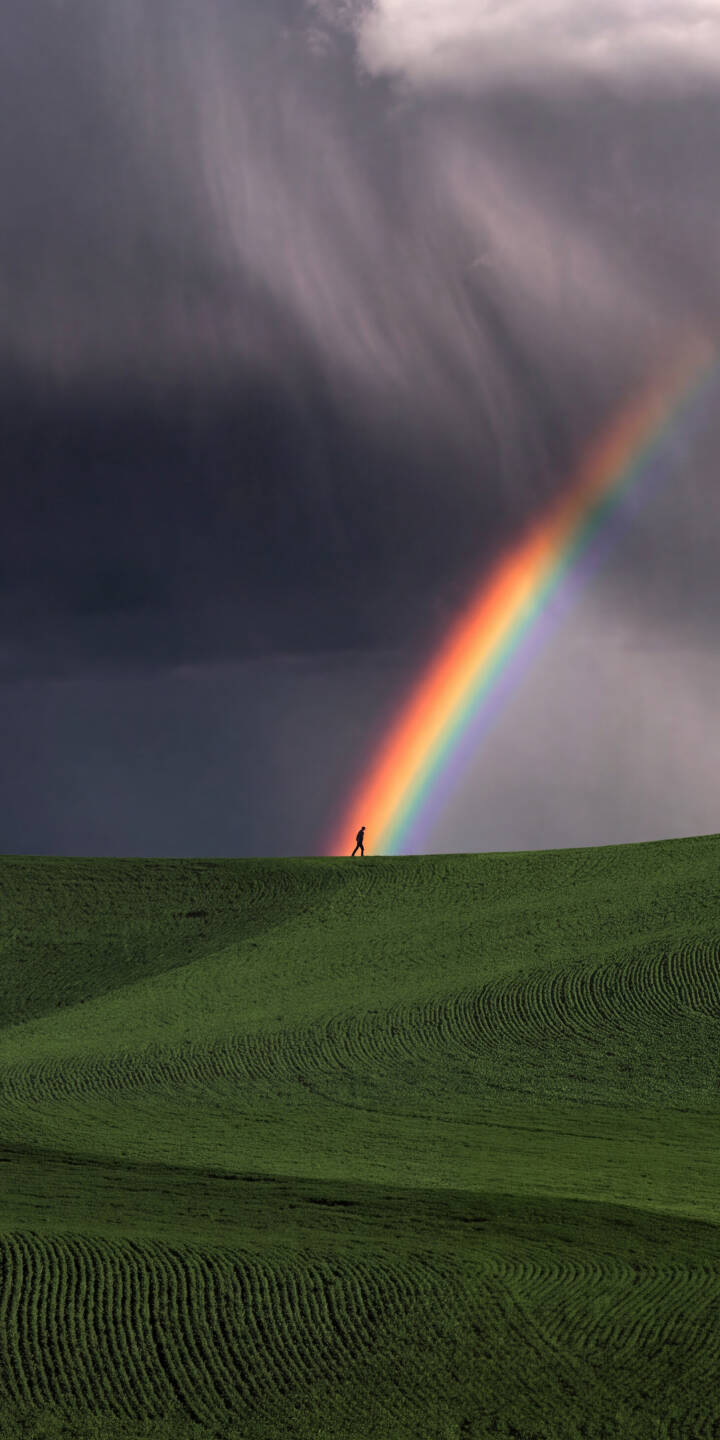 The vivid arc of a rainbow dramatically cuts through a brooding storm sky, illuminating rolling green hills and a solitary figure in this breathtaking 4K wallpaper. This stunning natural landscape wallpaper is perfect for your iPhone. | landscape storm rainbow iphone nature clouds hills wallpaper vibrant mobile 4k wallpaper hd wallpaper The vivid arc of a rainbow dramatically cuts through a brooding storm sky, illuminating rolling green hills and a solitary figure in this breathtaking 4K wallpaper. This stunning natural landscape wallpaper is perfect for your iPhone.