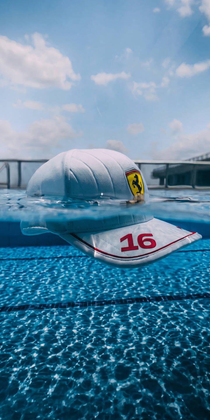 The white Ferrari cap, emblazoned with the iconic Prancing Horse logo and Charles Leclerc's number 16, floats peacefully on the vibrant blue water of a swimming pool in this captivating 4K wallpaper. This dynamic wallpaper, showcasing the cap partially submerged under a bright sky, is an excellent choice for any iPhone user and Formula 1 fan. | water pool iphone ferrari wallpaper charles leclerc formula 1 floating mobile 4k wallpaper hd wallpaper ferrari cap The white Ferrari cap, emblazoned with the iconic Prancing Horse logo and Charles Leclerc's number 16, floats peacefully on the vibrant blue water of a swimming pool in this captivating 4K wallpaper. This dynamic wallpaper, showcasing the cap partially submerged under a bright sky, is an excellent choice for any iPhone user and Formula 1 fan.